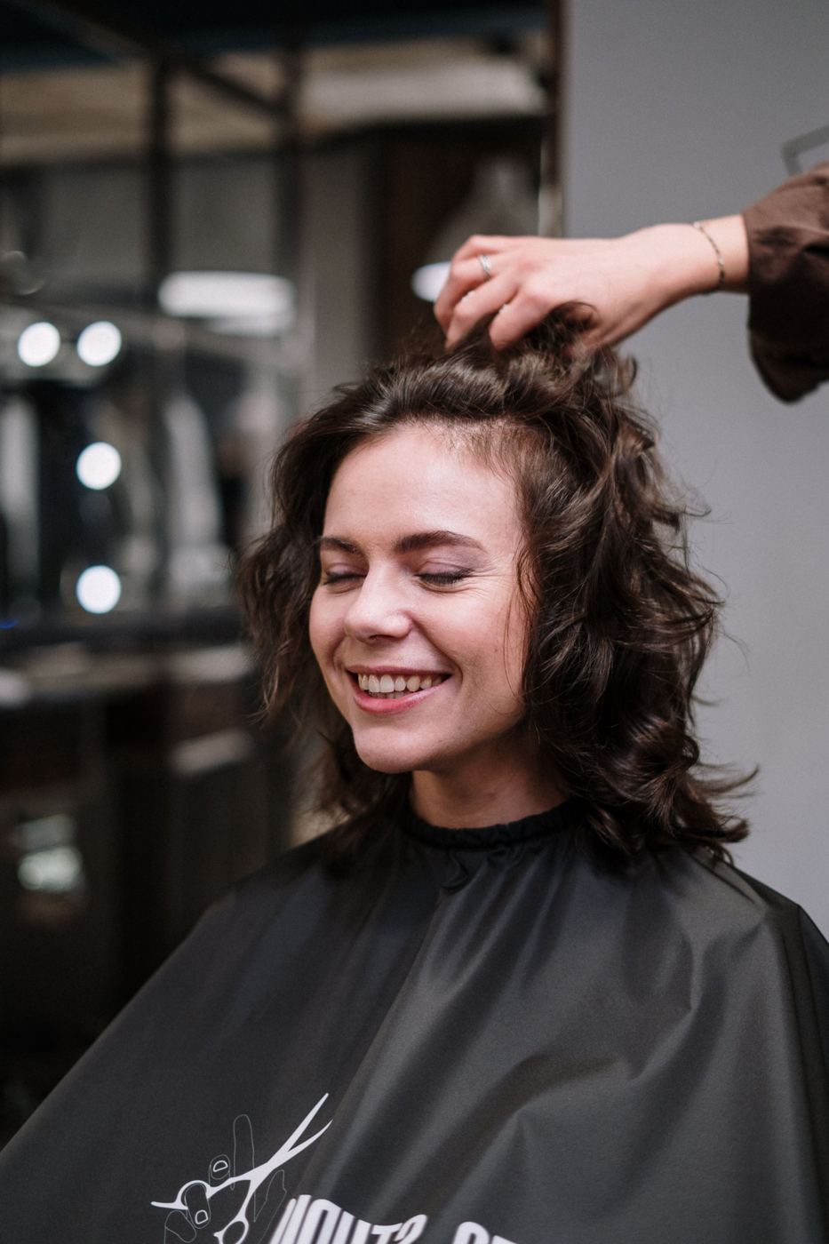 Cliente souriante aux cheveux bouclés pendant le coiffage